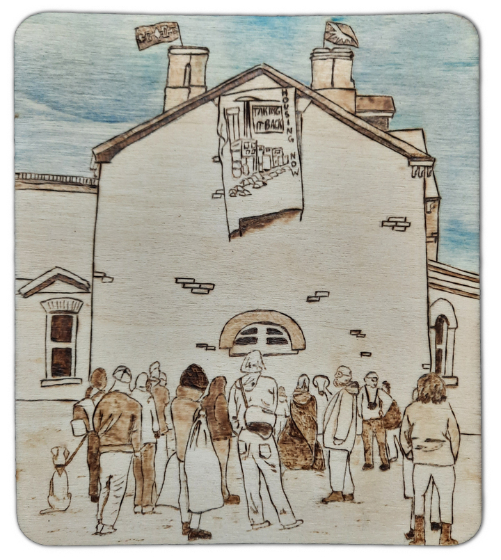 About 15 people gather in front a three story house. This is 230 sherbourn at the corner of Dundas and Sherbourne in Toronto. A large banner hangs from the roof